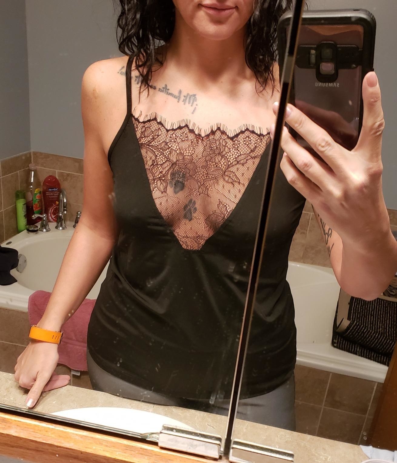 A reviewer in the black tank with a sheer lace panel forming a deep v-neck