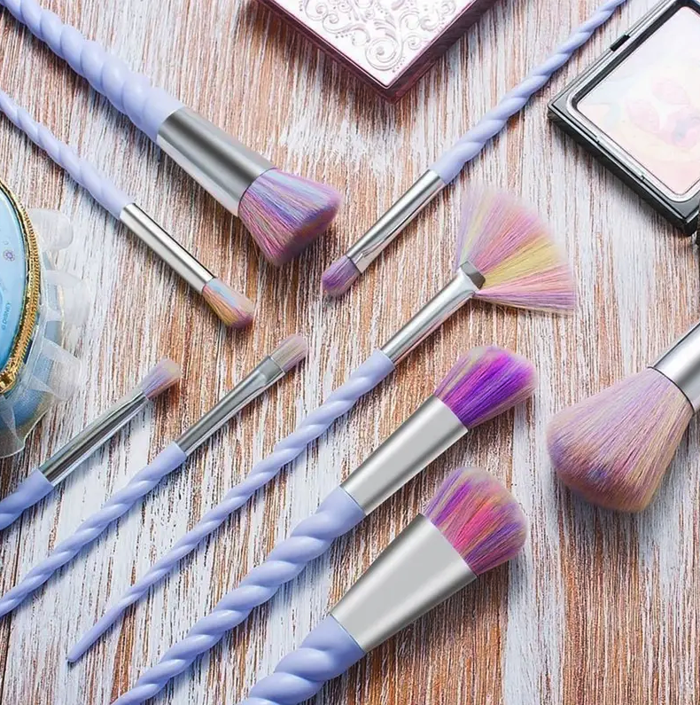 a makeup brush set with twisted purple handles that look like unicorn horns and rainbow bristles