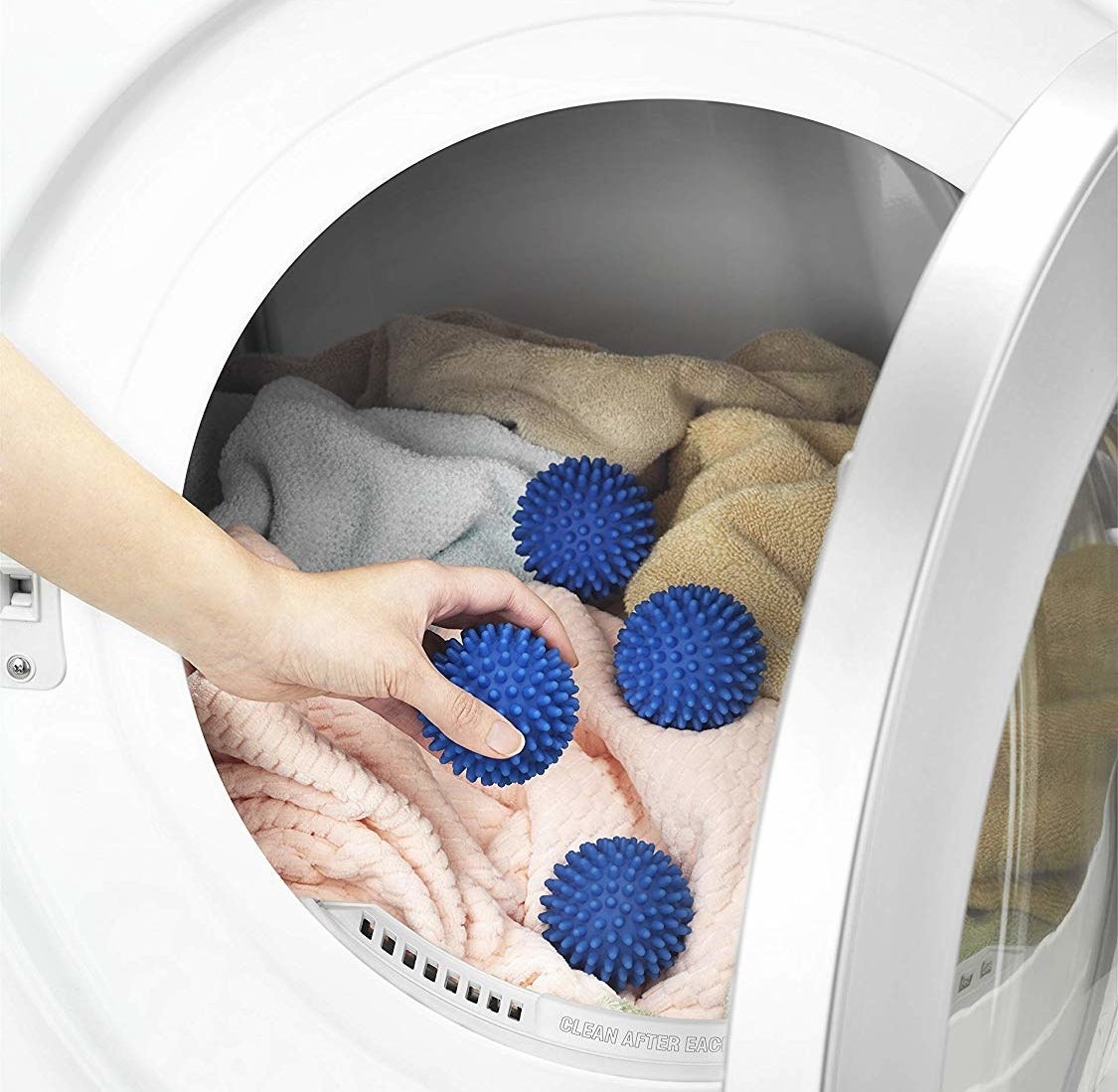 A person putting the dryer balls into their machine