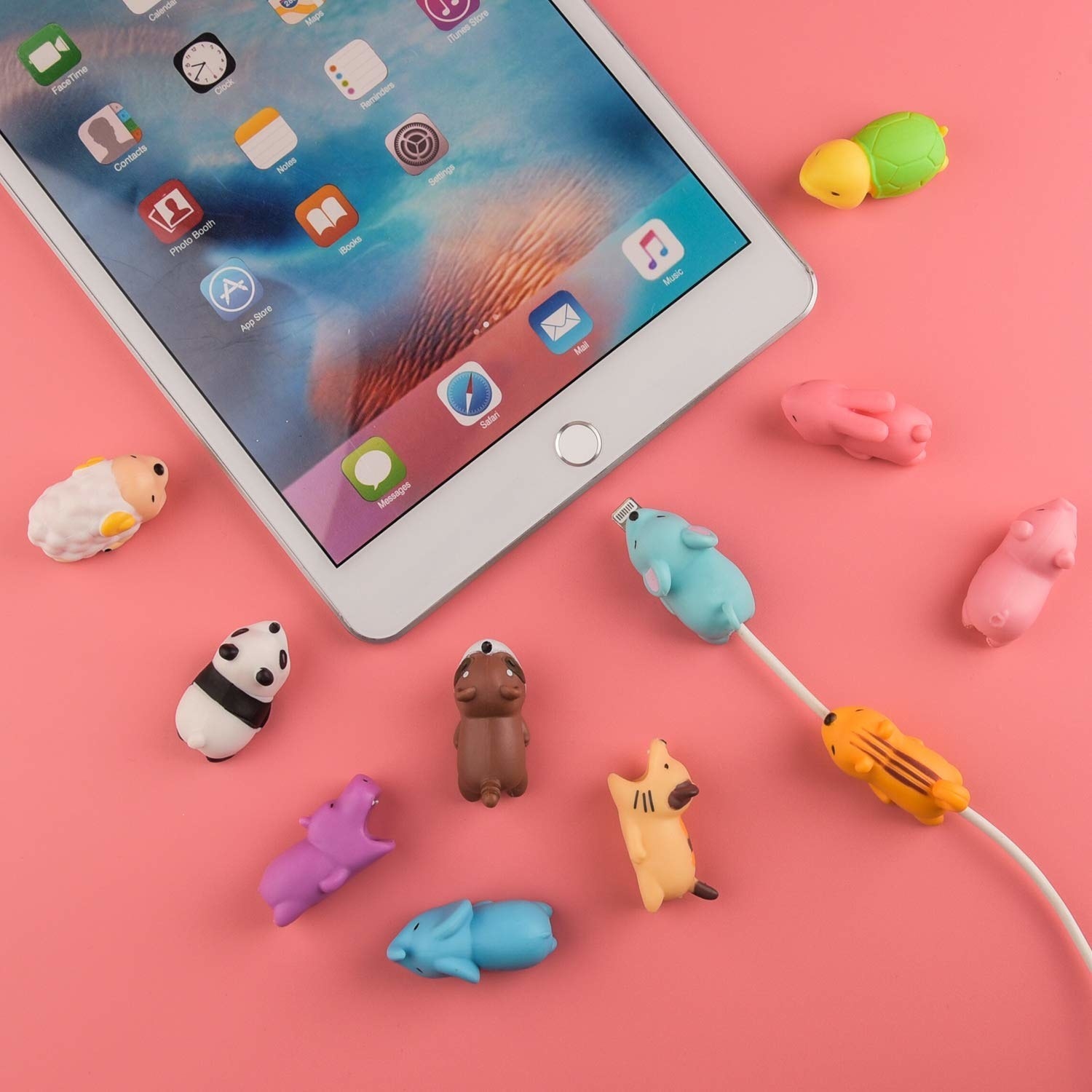 Several different animal cord protectors on a table, one attached to a cord being inserted into an iPad