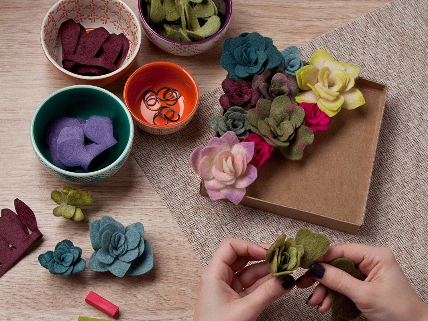 A person making felt succulents and putting them into the holder