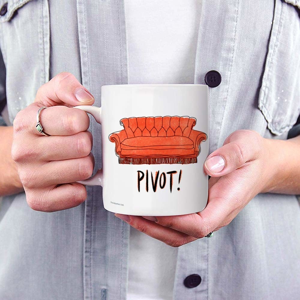 a white mug with a red couch on it and the word pivot!