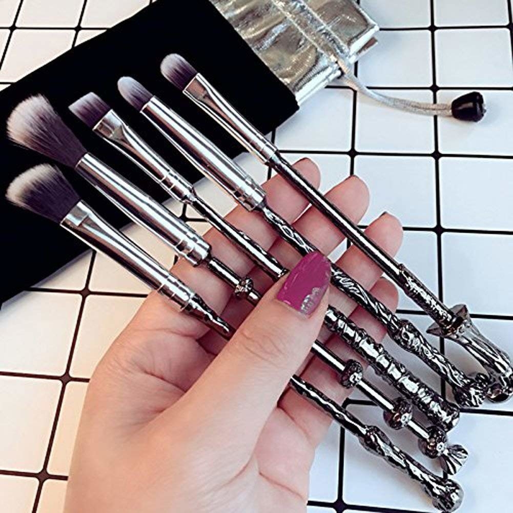 A person holding a five makeup brushes that look like magic wands in their hand