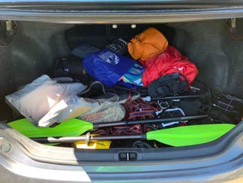 Reviewer photo of their messy trunk with oars, clothes, straps, and other stuff