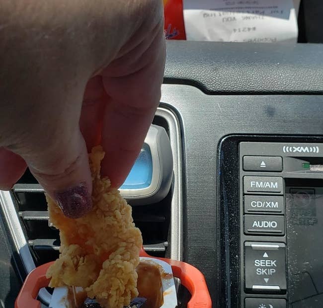 The clip attached to an air vent holding a sauce container