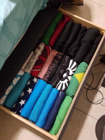 A reviewer's shirts folded neatly in a drawer, stacked sideways so they can see all the designs
