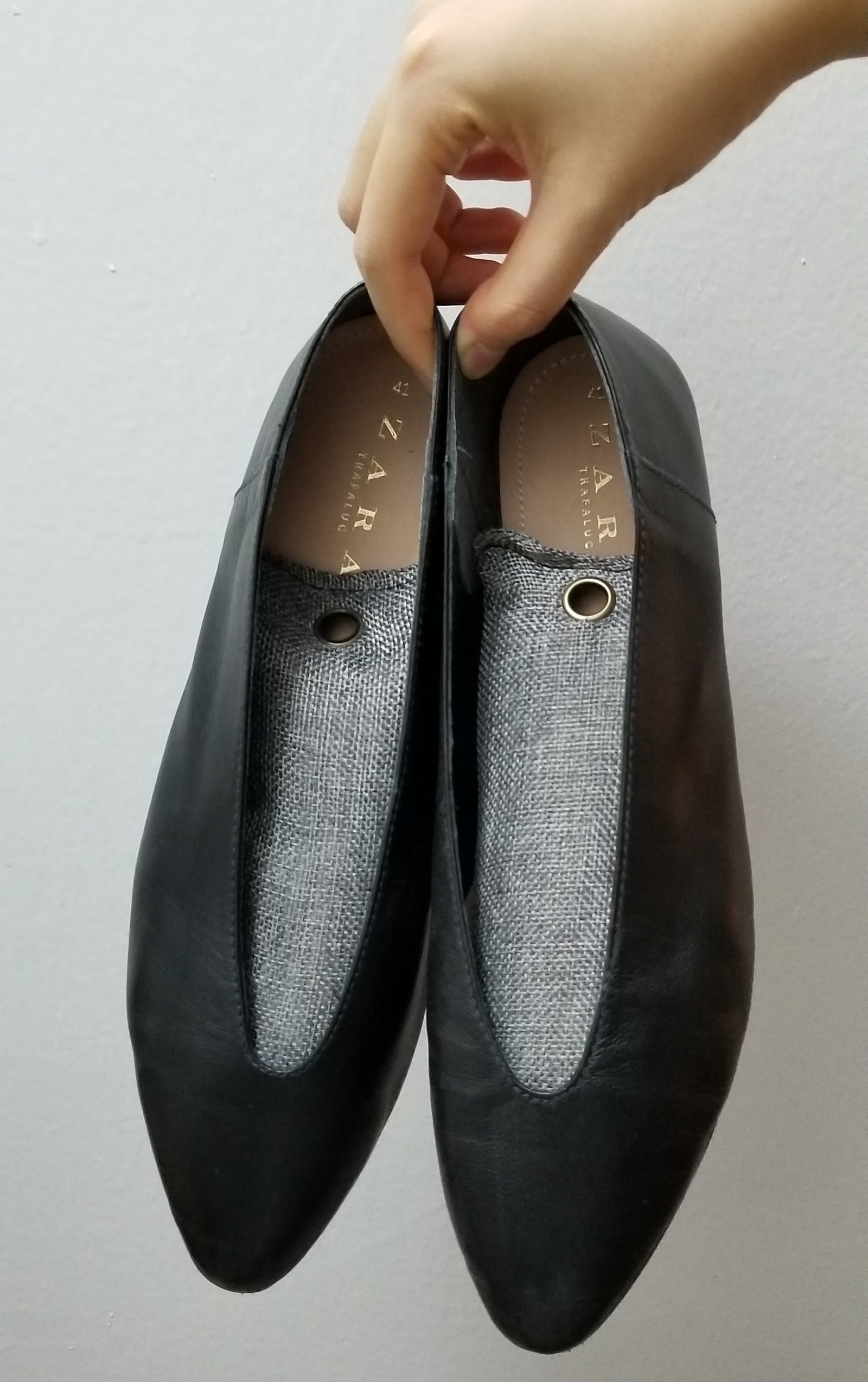 Hands holding a pair of flats with the charcoal deodorizers in each shoe 