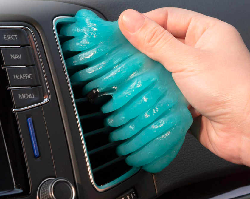 Person using gel putty to clean the AC inside their car 