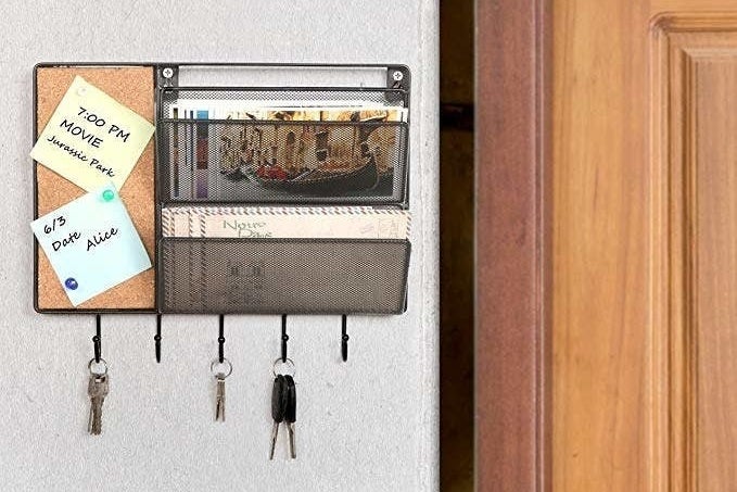 The black mesh mall sorter has a cork board, two mail slots, and five key hooks