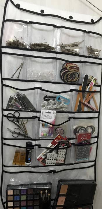 the hanging organizer being used to sort beauty items like hair clips, hair ties, nail stickers, makeup, and more 