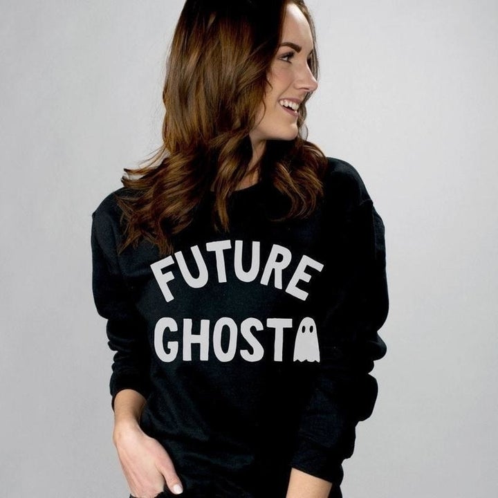 a model in a black crewneck sweatshirt that says "future ghost" on it next to a little ghost