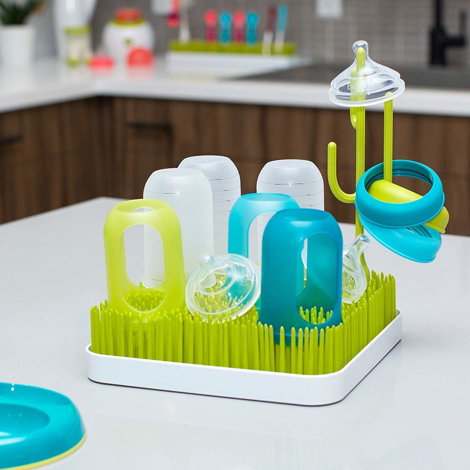 A dish mat with tall thin silicone sticks on it A cactus-shaped silicone hook sticks up in the middle