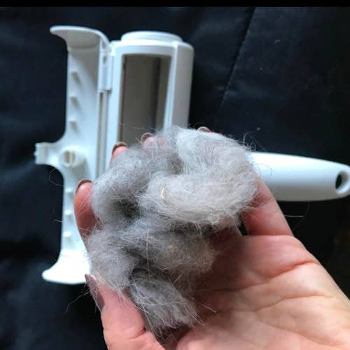 reviewer's hand removing a clump of hair from the roller