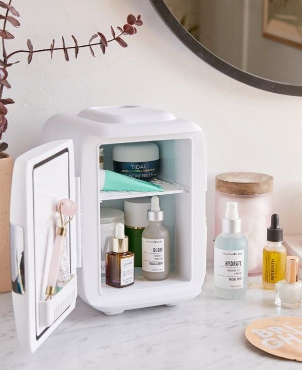 the mini fridge open with tons of beauty products inside on the shelf