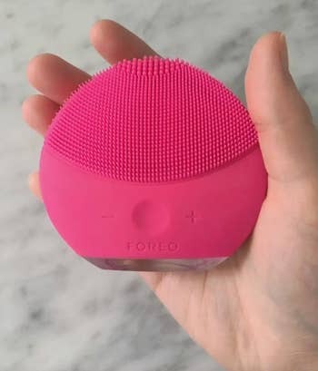 the reviewer holding the round pink cleaning brush