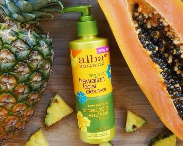 The pump bottle of the cleanser next surrounded by tropical fruit