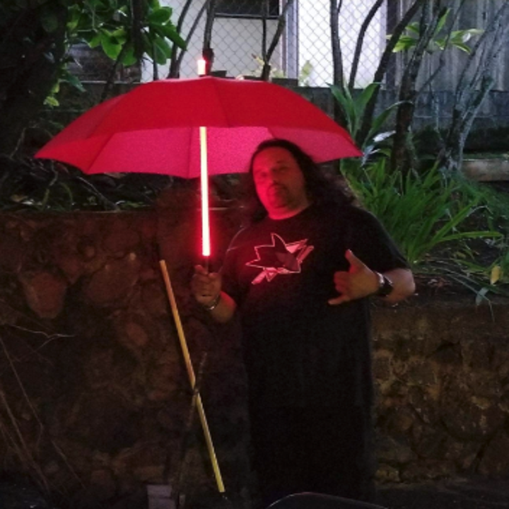 a reviewer holding a red umbrella with a lightsaber handle