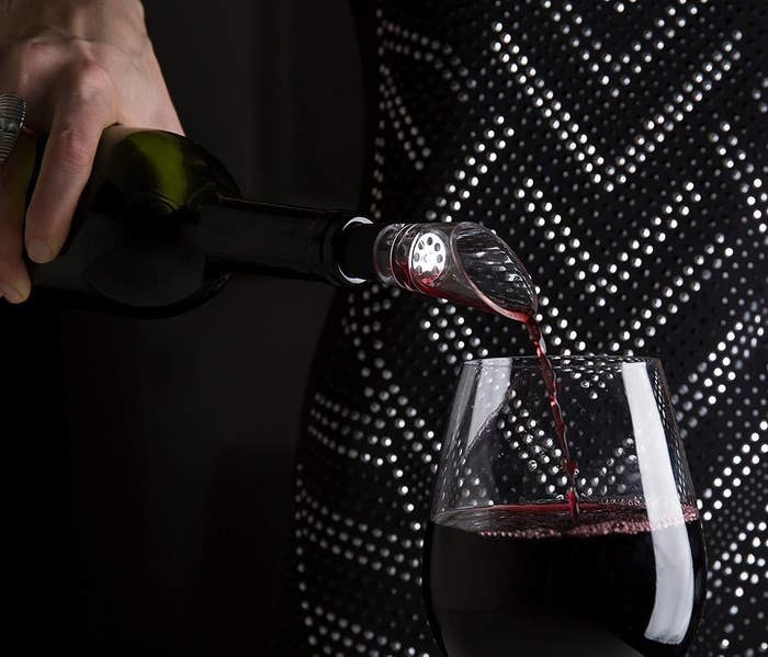 model pouring a glass of wine with the aerator on the bottle 