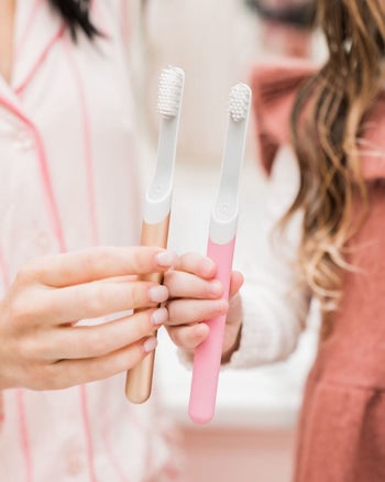 two models holding rose gold and pink toothbrushes