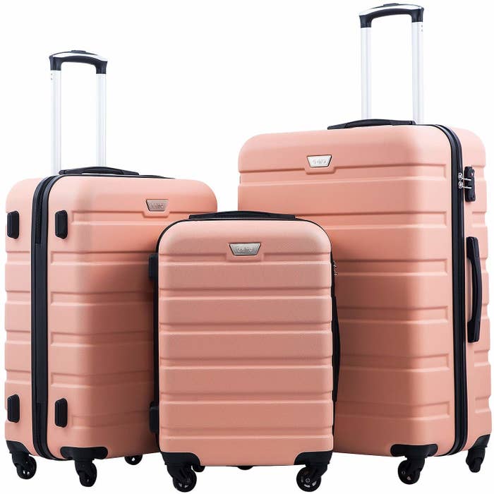 Three pink hard shell suitcases in small, medium, and large