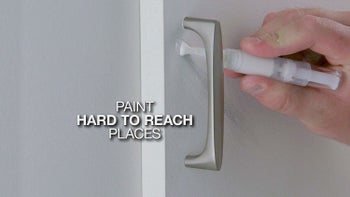 a person using the paint pen to apply white paint to a door