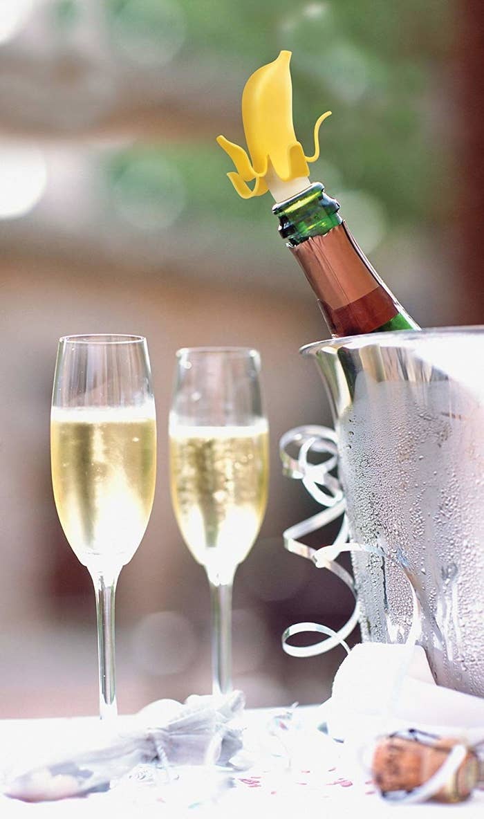 A champagne bottle chilling in a bucket and topped with a banana-shaped stopper