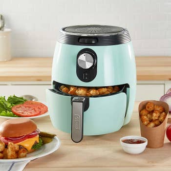 The light blue air fryer with basket filled with tater tots