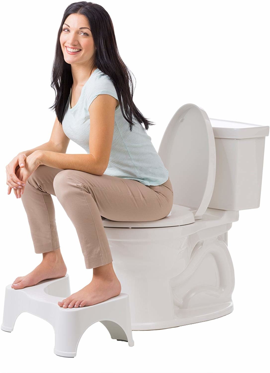 model sitting on a toilet with their feet elevated on the squatty potty