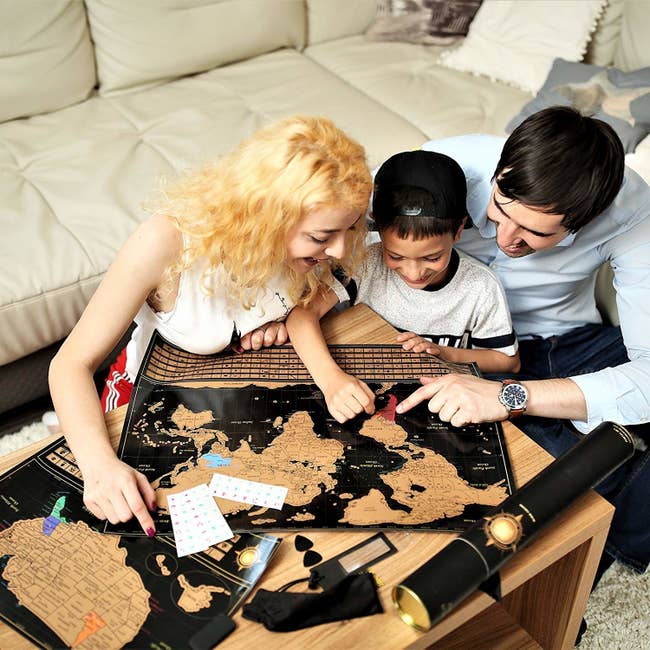 A family scratching off the gold map on a black background
