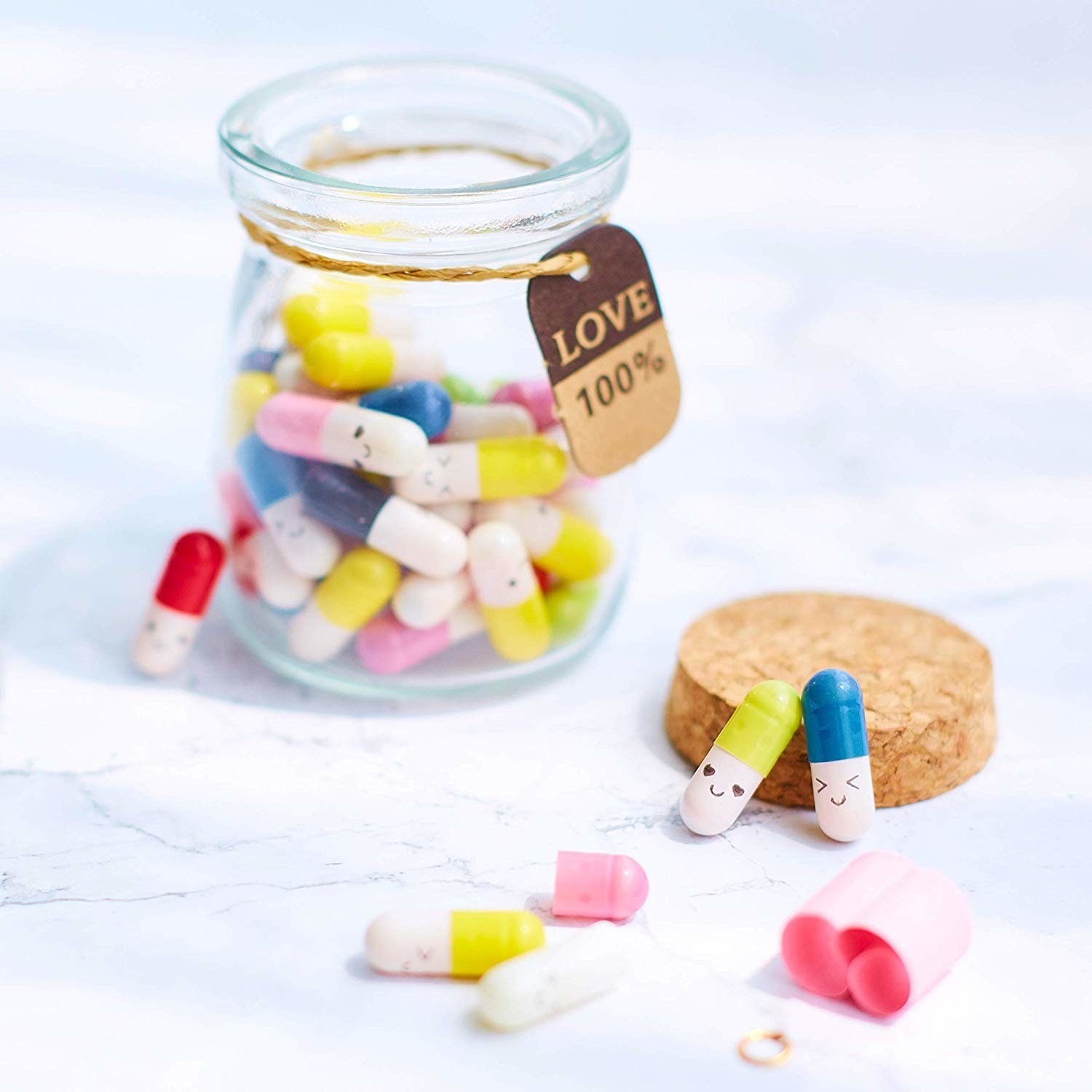 Small glass jar with cork top and several faux pills with funny faces that can be opened up 