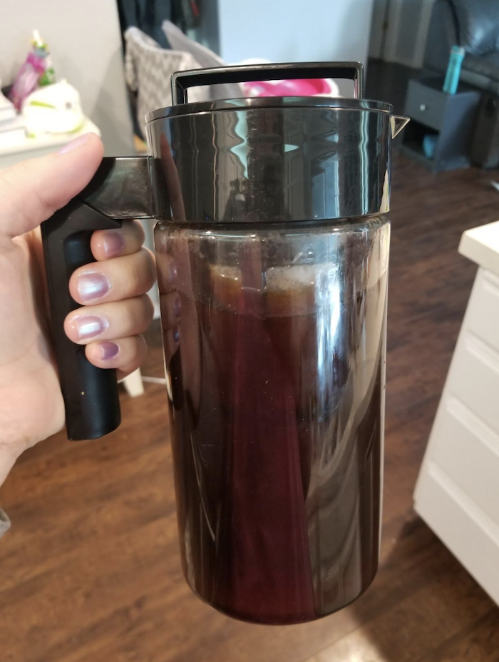 reviewer holding the cold brew which is shaped like a tall mug