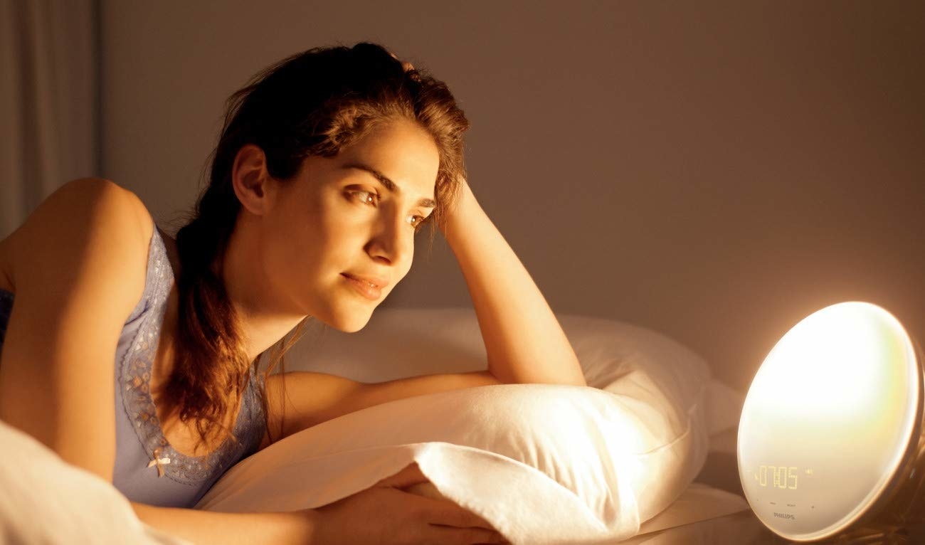 A model in bed with the clock glowing warm, sunny light