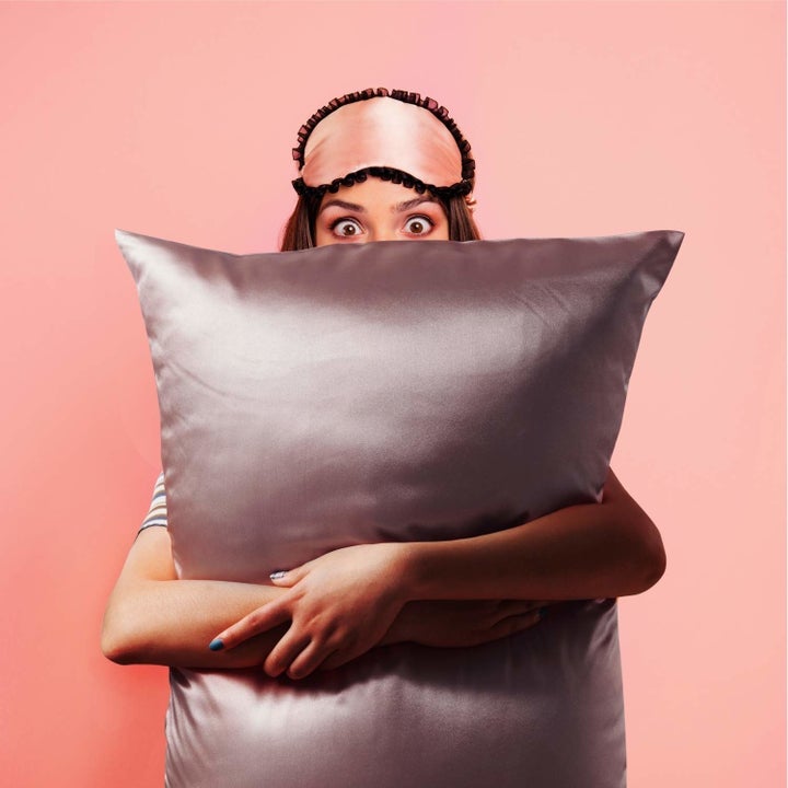 model holding a pillow with the gray satin case on it 