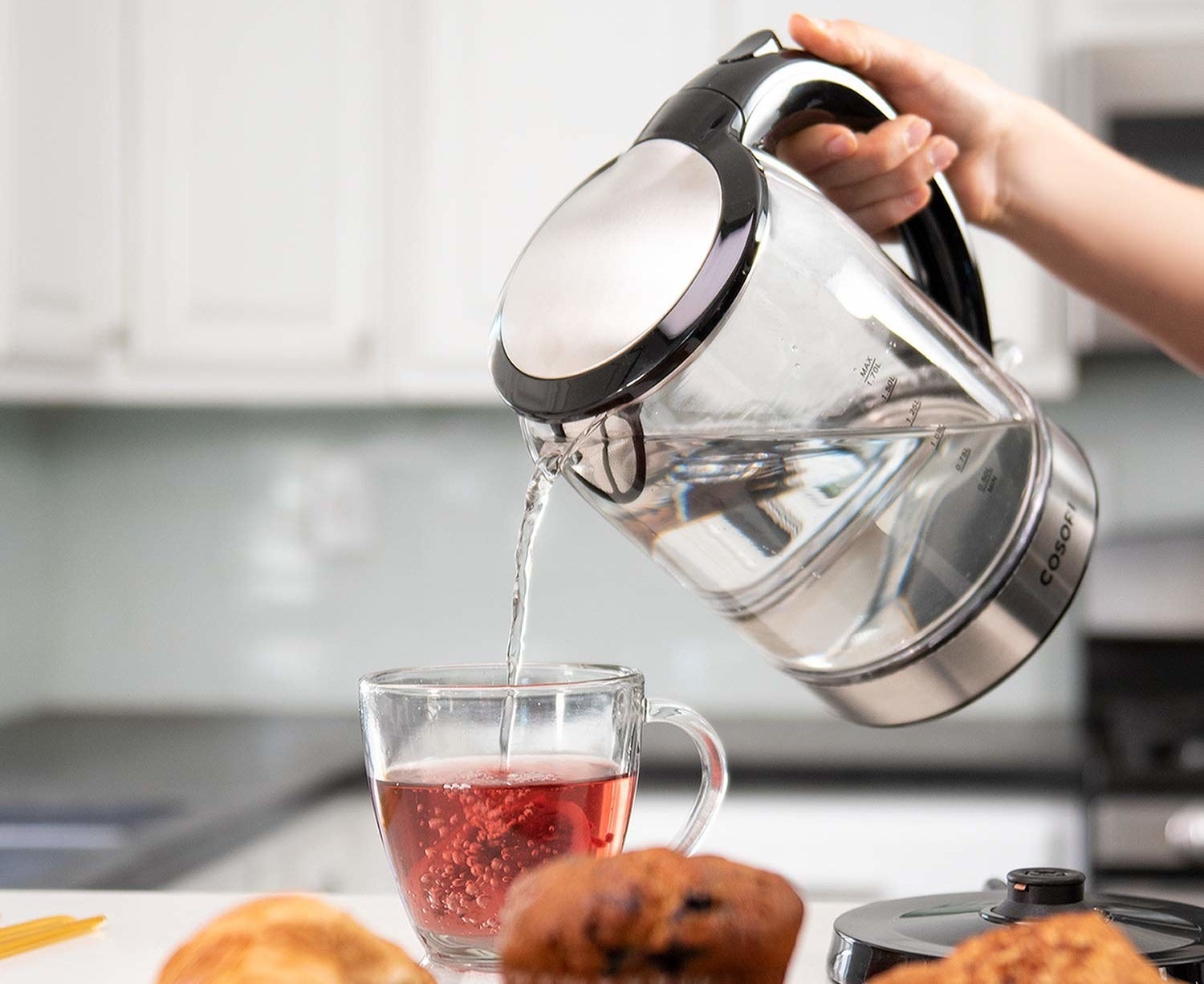 A model pouring water out of the transparent glass electric kettle into a tea cup