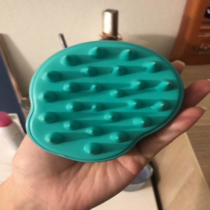 the massager in teal with silicone bristles 
