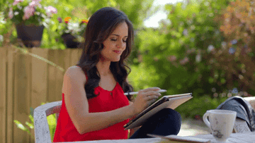 Gif of a person sitting outside and using a pen to mark things in a notebook 