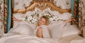 Gif of Kirsten Dunst in Marie Antoinette settling into a grand bed 