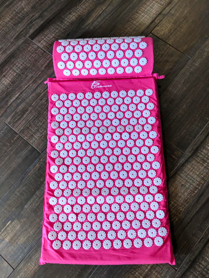 Pink and white acupressure mat on the floor