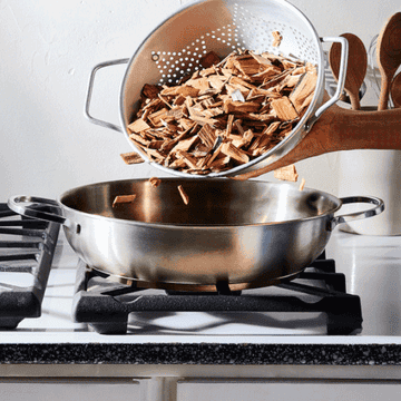 Gif of wood chips inside pan with meat placed above it on rack and lid closed