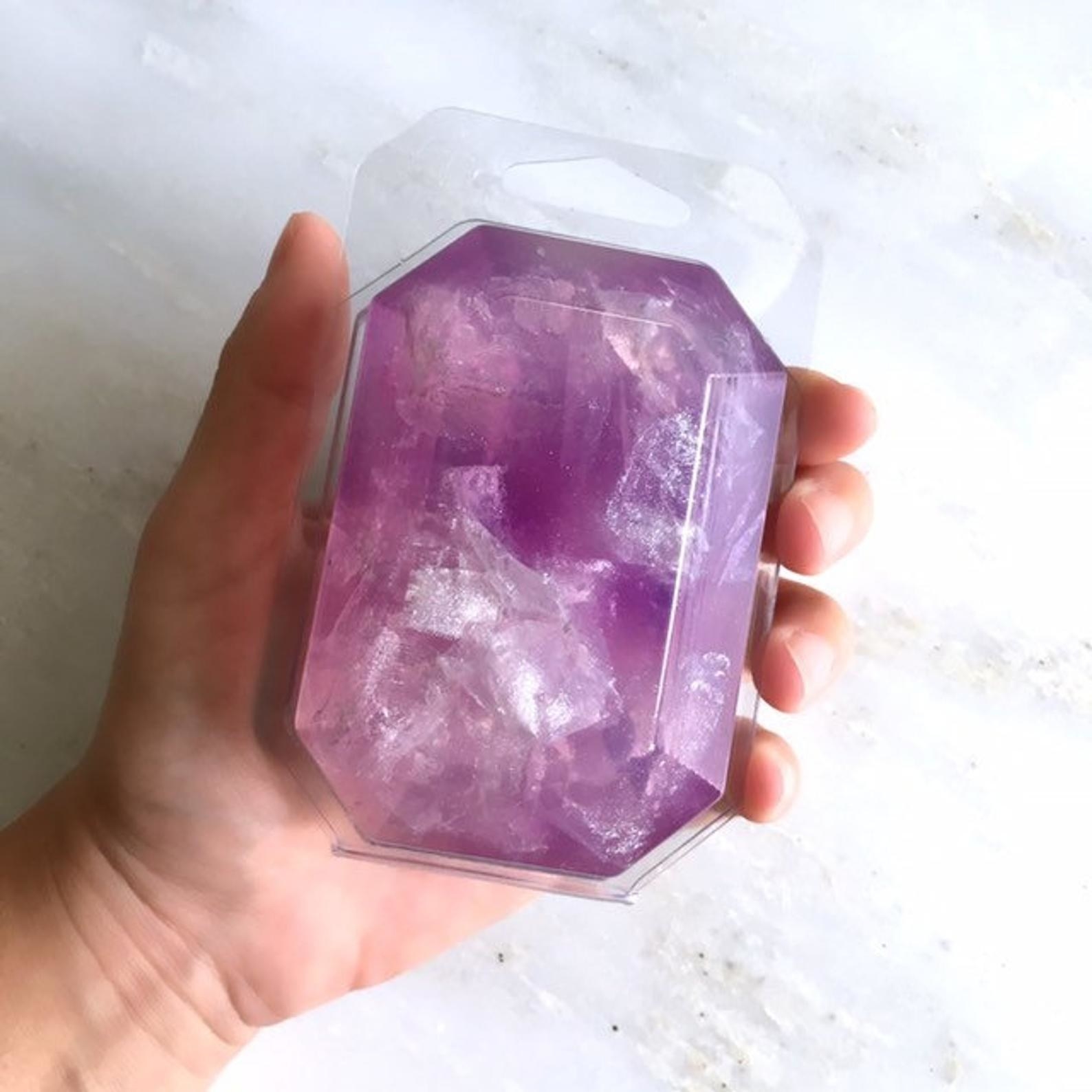 hand holding a gemstone-shaped boar of soap in purple and pink irridescent
