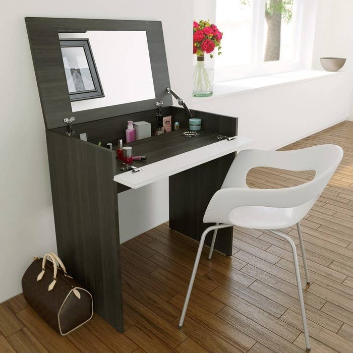 the storage vanity with a mirror on the underside and chair in front of it 