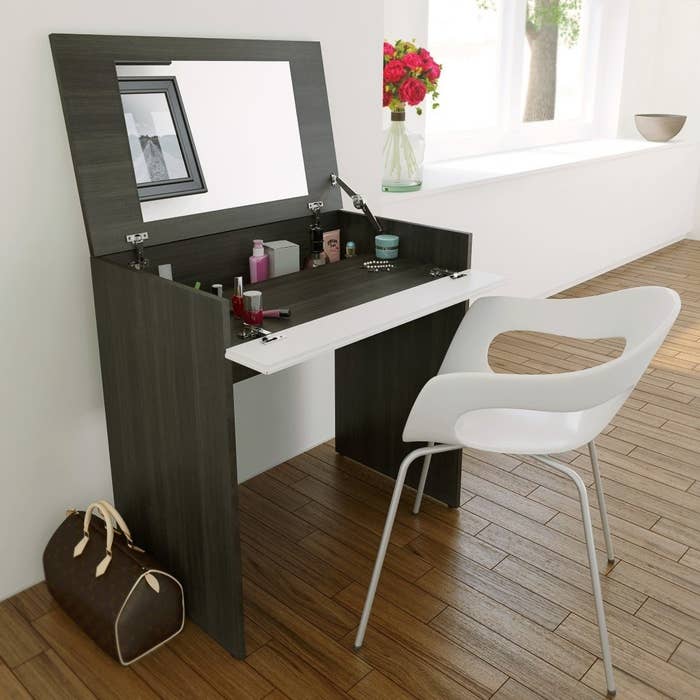 the storage vanity with a mirror on the underside and chair in front of it