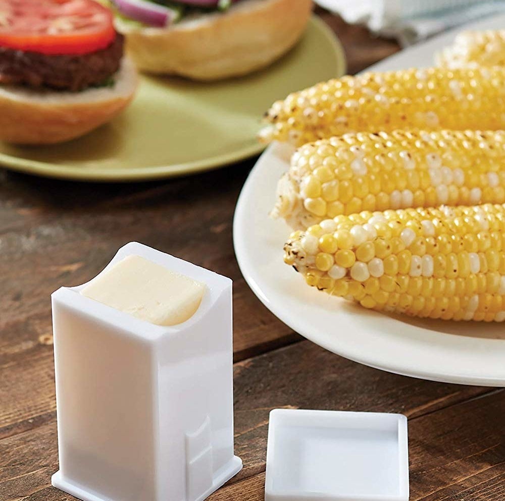 The butter spreader next to a plate of corn