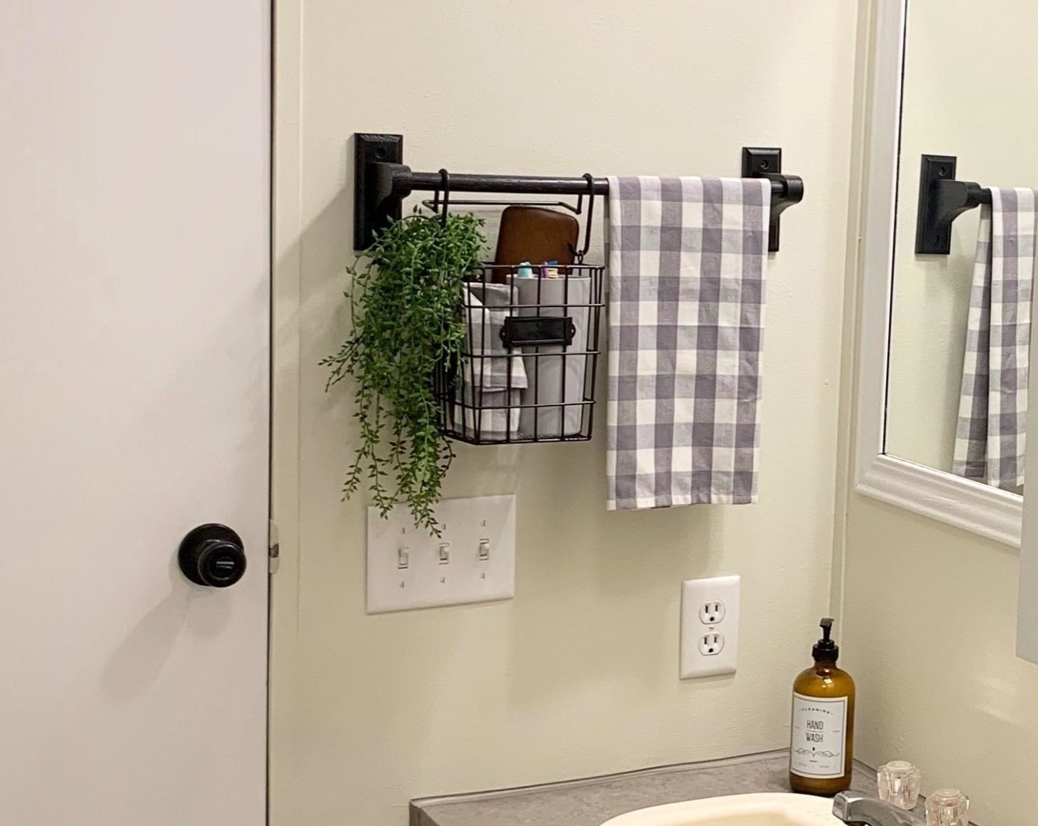 The basket hung from a towel bar and holding a variety of items as well as a plant