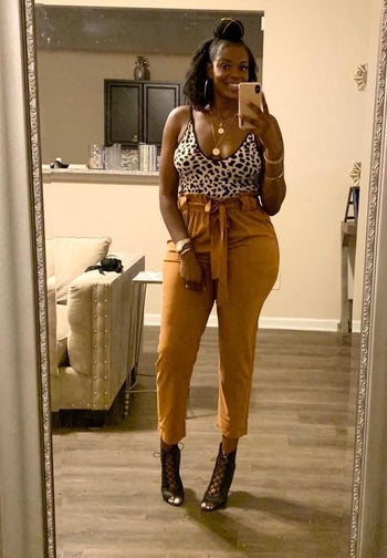 reviewer wearing the mustard-colored pants with a dressy tank top and black strappy heels