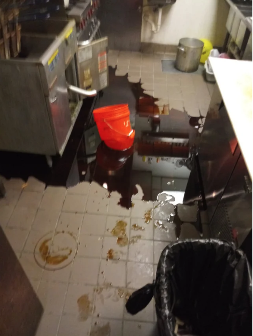 A melted bucket with grease seeping out of it and all over the kitchen floor