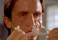 A GIF of Christian Bale from American Psycho. He&#x27;s peeling a mask off his face.