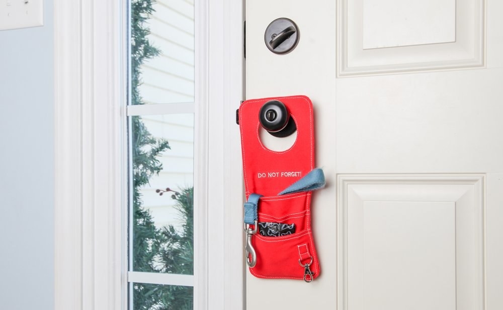 The door knob organizer with keys and other items in its pockets while it hangs from a door knob