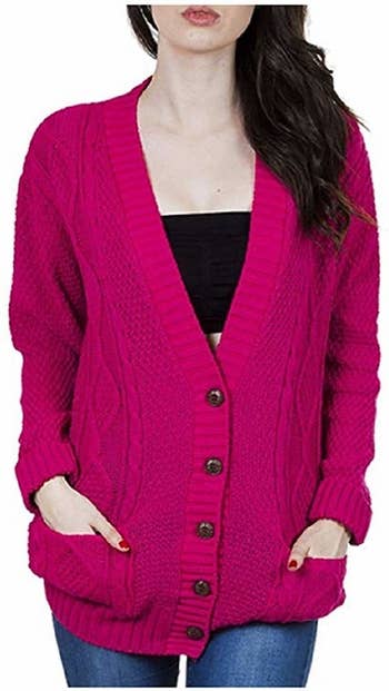 A model wearing the cardigan in hot pink with their hands in the pockets