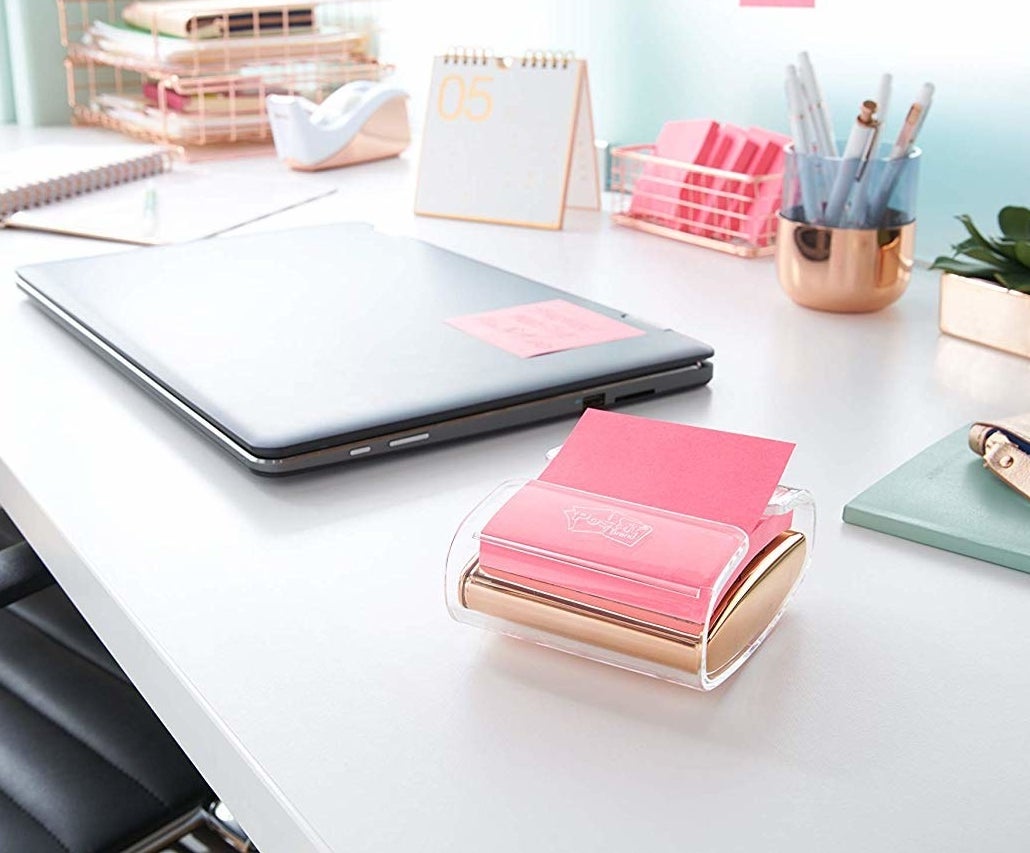 A stack of memo notes sitting in a small square dispenser on a desk